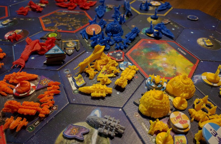 A close-up view of a colorful and detailed board game layout featuring various brightly colored plastic pieces representing spaceships and starbases, arranged on a galaxy-themed game board with hexagonal spaces, alongside cards and tokens.