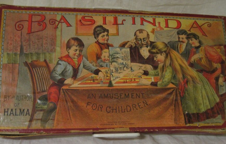 Vintage "BASILINDA" board game cover featuring illustrations of a family engaging in play, with text "An Amusement for Children" and "By Author of Halma." The cover shows wear and tear indicative of its age.