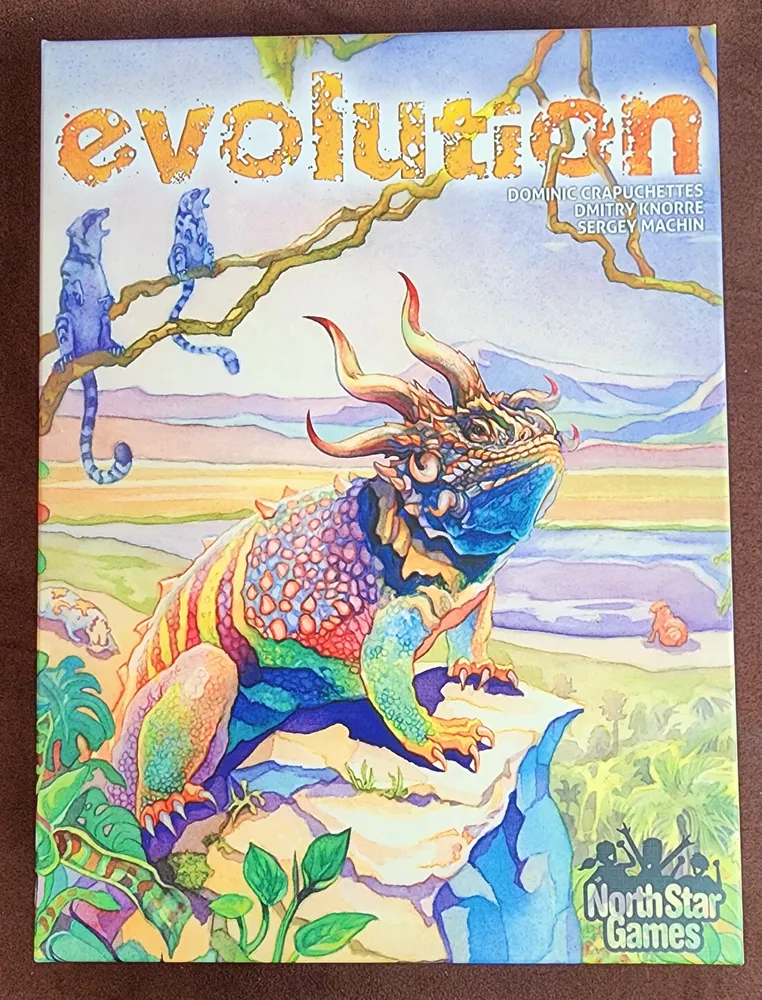 Board game cover titled "Evolution" with vibrant illustration of a fantastical lizard-like creature on a rocky landscape, surrounded by plant life and other smaller creatures, with the creators' names and North Star Games logo at the bottom.