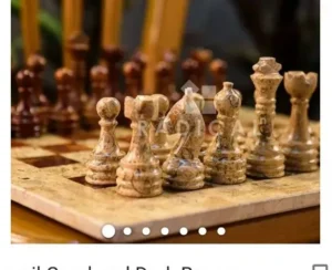 A close-up of a marble chess set with white pieces in focus and brown pieces in the background.