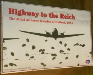 A poster titled "Highway to the Reich - The Allied Airborne Invasion of Holland, 1944" featuring the silhouette of a military airplane against a white background with scattered silhouettes of paratroopers descending, and the text "Time: 1300 Hours, September 17, 1944" at the bottom. The logo of Decision Games is in the lower right corner.