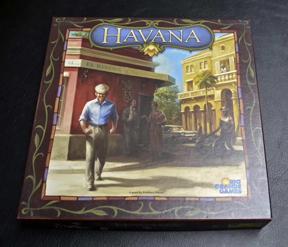A "Havana" board game box resting on a black surface, with artwork depicting a Cuban street scene and people in vintage attire.