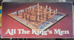 A worn board game box for "All The King's Men" featuring an image of a chess-like game board with various standing figures positioned on it.