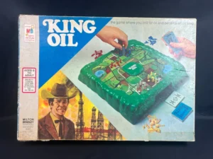 Vintage "King Oil" board game box with illustrated graphics depicting a man in a cowboy hat, oil derricks, and players engaging with the game pieces on the 3D board, indicating it is a strategy game for ages 9 to adult.
