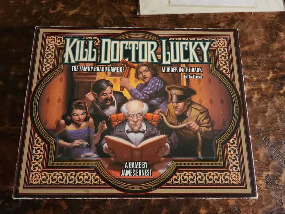 A "Kill Doctor Lucky" board game box depicting cartoon-style characters -- a young woman, two men, an elderly man, and a person in the shadows -- seated around a room, with the elderly man reading a book, oblivious to the others' malicious intentions. The cover also includes the subtitle "Murder in the Dark" and text indicating it is for 3-7 players and designed by James Ernest.