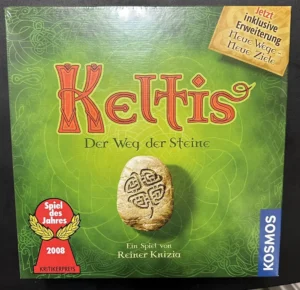 Board game cover for "Keltis" with the subtitle "Der Weg der Steine" featuring a stylized stone with Celtic designs, a "Spiel des Jahres 2008 Kritikerpreis" award ribbon, and a label stating "Jetzt inklusive Erweiterung Neue Wege - Neue Ziele." The game is noted to be from Kosmos and created by Reiner Knizia.