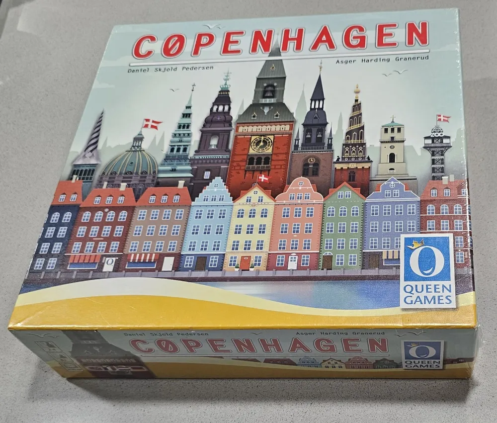 A board game titled "COPENHAGEN" in a box with colorful artwork depicting stylized buildings typical of Copenhagen's architecture, by Queen Games.