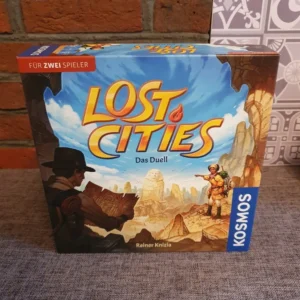 A "Lost Cities" board game box by Kosmos for two players, titled "Das Duell," featuring artwork of an explorer with a map and a guide pointing towards ancient ruins.