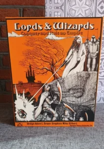 A boxed board game titled "Lords & Wizards: Conquer and Rule an Empire" with fantasy-themed illustrations on the cover, including a wizard, knights, a castle, and a dragon. Design credits go to Adam L. Gruen and graphics by Mike Gilbert from Fantasy Games Unlimited, Inc.
