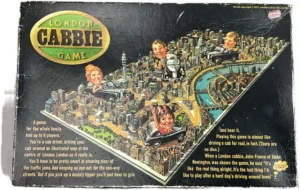 Picture of the board game "London Cabbie Game" box cover featuring an illustrated map of central London with cartoonish taxi driver heads popping out, a description of the game for up to 6 players, and a customer quote. Price sticker in the top right corner.