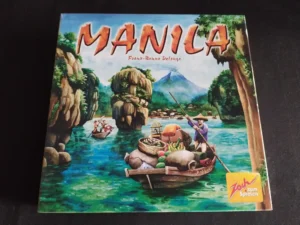 Board game cover titled "MANILA" with an illustrated river scene showing boats, traders, and tropical scenery, including a volcano in the background; a logo in the bottom right corner reads "Zoch zum Spielen".