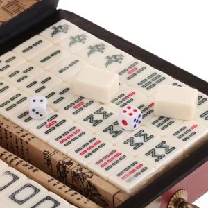 A close-up of Mahjong tiles arranged on a table beside two dice, with some tiles and tile stacks showing oriental characters and symbols in the background.