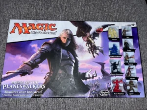 A "Magic: The Gathering - Arena of the Planeswalkers, Shadows over Innistrad" board game box, featuring fantasy artwork and miniature game pieces for characters like Avacyn, Jace, Sorin, and others. The game is intended for 2-4 players, aged 10 and up.