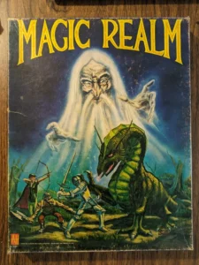 Alt-text: The image shows the cover of a game titled "MAGIC REALM," featuring a large illustration of a wizard-like figure with a flowing white beard overshadowing a scene of three adventurers fighting a green dragon. The artwork has a vintage fantasy style and is printed with the Avalon Hill Game Company logo and a product number at the bottom.
