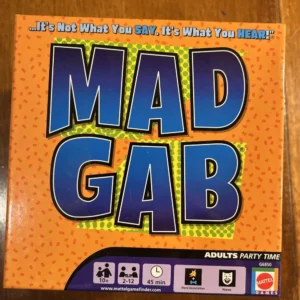The image shows the game box of "MAD GAB", with the tagline "It's Not What You SAY, It's What You HEAR!" There are icons indicating the game is suitable for ages 10 and up, 2-12 players, and a duration of approximately 45 minutes. The box also has icons for word association and humor, and includes the Mattel Games logo. The website "www.mattelgamefinder.com" is mentioned at the bottom.