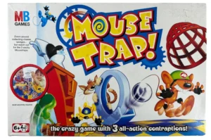 Box cover of the board game "Mouse Trap" by MB Games, featuring colorful text, cartoon mouse characters, a cage trap, and an image of two children playing the game. The tagline reads "the crazy game with 3 all-action contraptions!" and there is a note that adult assembly is required, with an age recommendation of 6+.