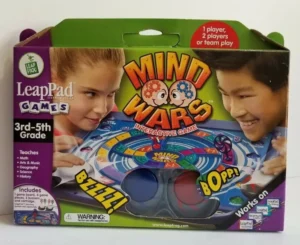A boxed LeapPad learning system game titled "Mind Wars Interactive Game" for 3rd to 5th grade, featuring two smiling children playing the game, with listed educational topics such as math, arts & music, geography, science, and history. The product boasts compatibility with LeapPad laptops and includes game pieces, board, and cartridge.