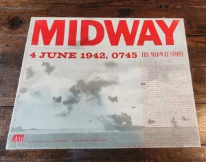 Board game "Midway" by The Avalon Hill Company, with a cover featuring large red text "MIDWAY" and "4 JUNE 1942, 0745 THE MIDWAY STORY" on a background depicting a grayscale image of ocean skies with smoke, placed on a wooden surface.