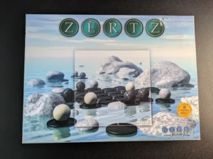 The image shows a "ZERTZ" board game box with a serene sea landscape in the background, featuring rocks in water and black and white gaming pieces on the front. There's a Mensa Select seal on the bottom right and the GIPF project logo at the bottom center.