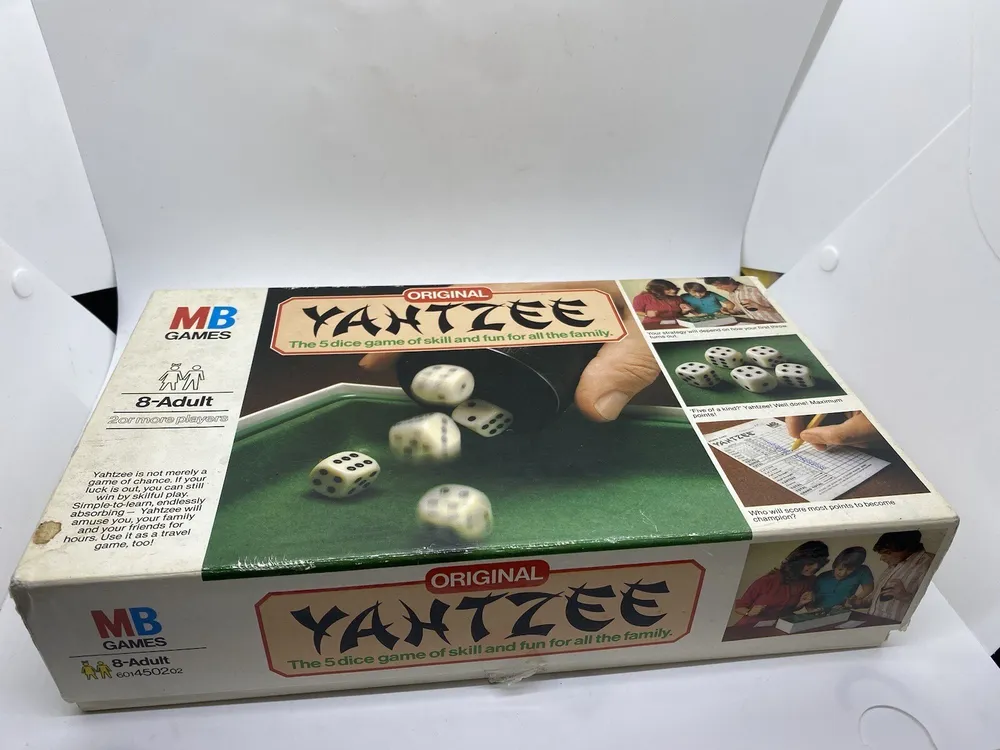 An "MB Games" original Yahtzee board game box for ages 8 to adult, displaying the game's title, dice images, and people playing the game, on a white background.