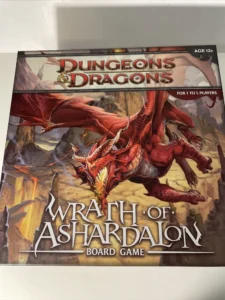 A "Dungeons & Dragons: Wrath of Ashardalon" board game box featuring an illustration of a red dragon, with text indicating it is suitable for ages 12+ and 1 to 5 players.