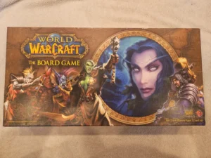 "World of Warcraft: The Board Game" box cover featuring vivid artwork of fantasy characters, including an orc, elf, and human knight around a central figure of a night elf woman's face.