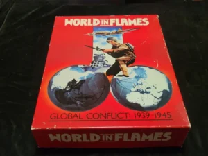 A "World in Flames" board game box with a soldier graphic and a split globe, indicating a WWII theme, laying on a black surface.