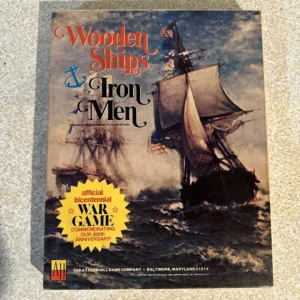 A worn board game cover titled "Wooden Ships & Iron Men" depicting a painted scene of a sailing ship on rough seas. A yellow starburst sticker reads "official bicentennial WAR GAME commemorating our 200th anniversary!" from The Avalon Hill Game Company.