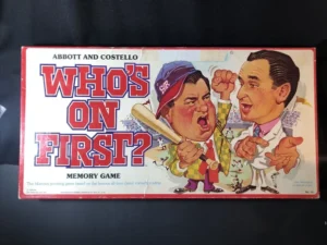 A vintage "Abbott and Costello Who's on First?" memory game box featuring illustrated caricatures of a shouting man in a baseball cap and a man in a suit pointing, with text and a cluttered baseball scene in the background.