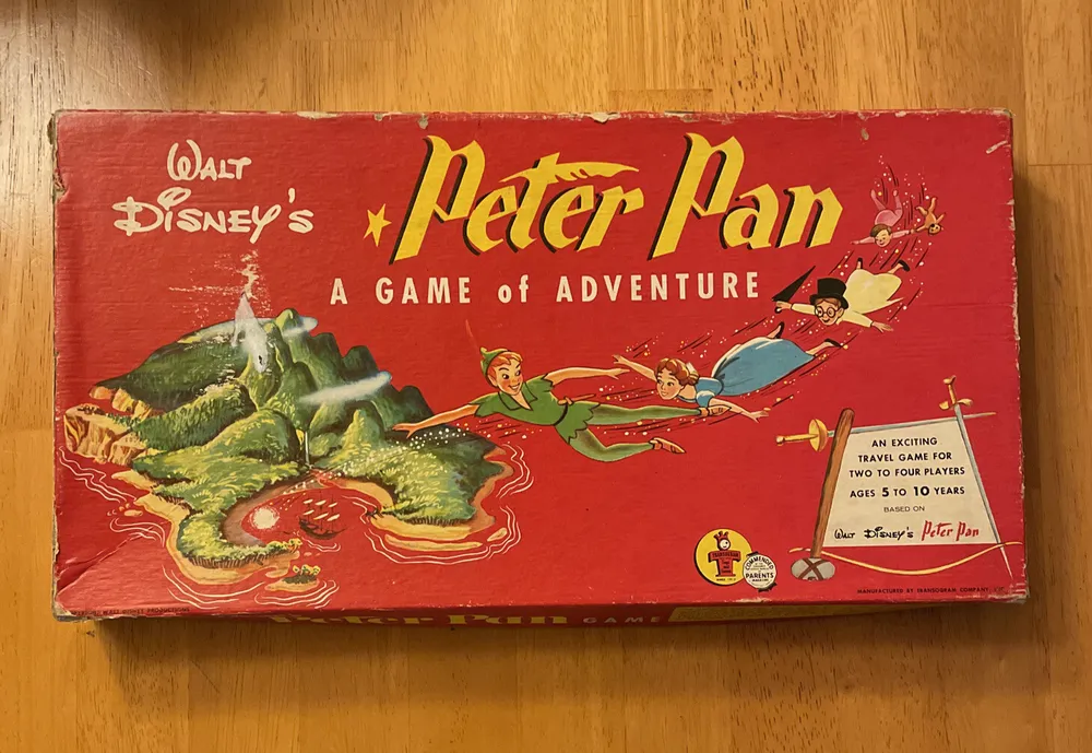 Vintage "Walt Disney's Peter Pan: A Game of Adventure" board game box with illustrations of flying characters and a Neverland scene, for ages 5 to 10, showing signs of wear.