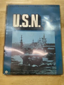 A worn board game box for "U.S.N.: The War in the Pacific 1941-43," an historical simulation game, featuring an image of naval warships on the cover.