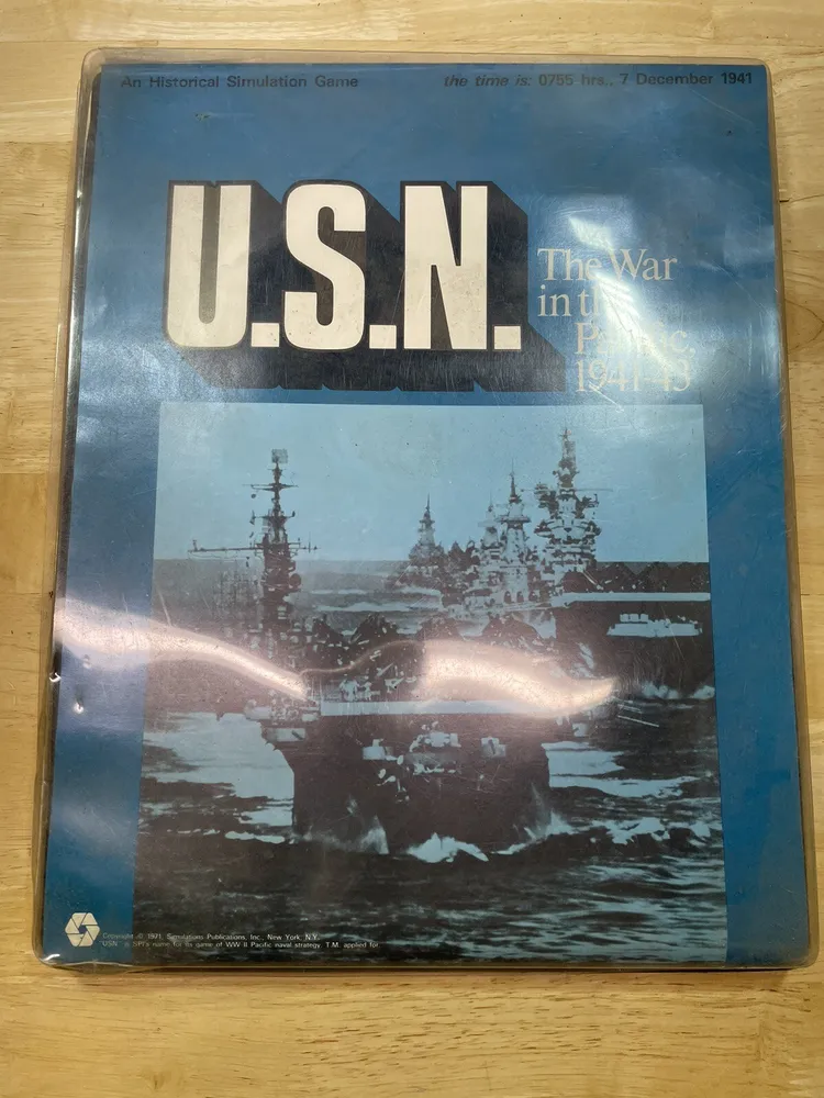 A worn board game box for "U.S.N.: The War in the Pacific 1941-43," an historical simulation game, featuring an image of naval warships on the cover.