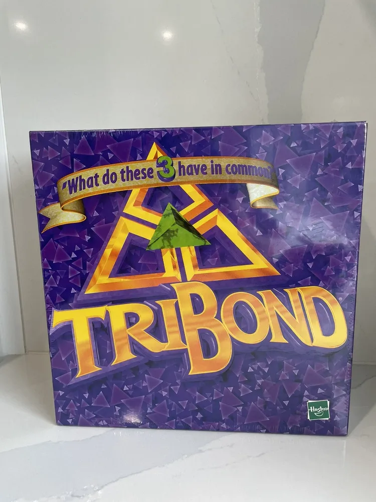A "Tribond" board game box with the tagline "What do these 3 have in common" displayed on a purple geometric pattern background, placed on a marble surface.