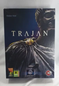 Box cover of the board game "Trajan" featuring an image of a Roman statue, with the name Stefan Feld at the top and award badges for "Game of the Year 2012" and "AMMONIT" at the bottom.