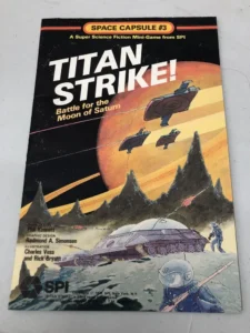 Alt text: A worn cover of the "TITAN STRIKE! Battle for the Moon of Saturn" board game, showing illustrated spacecraft and astronauts on a lunar landscape with Saturn and its rings in the background.