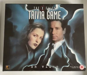 Box cover of "The X-Files Trivia Game on video," displaying two characters with a cloudy, blue-tinted backdrop, featuring the text "First Edition: Seasons 1-5" and a "15" age rating symbol.