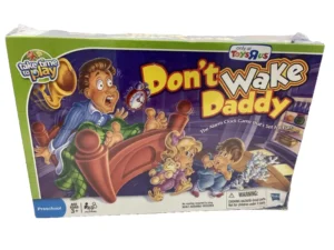 A "Don't Wake Daddy" board game box showing an illustrated startled man sitting up in bed with children tiptoeing around, for ages 3+, branded as a Toys"R"Us exclusive.