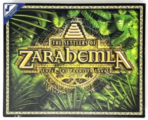 Board game cover with the title "The Settlers of Zarahemla" surrounded by ornate borders and lush green foliage, with the subtitle "Enter the Promised Land" below, and the logo of "Inspiration Games" in the top left corner.