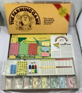 "The Farming Game" board game box opened to display the game board, paper money, plastic game pieces, cards, and an instruction sheet on a white background.