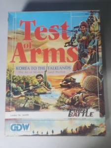 A board game cover titled "Test of Arms" with illustrated scenes of military combat, featuring soldiers in various action poses, tanks, and helicopters, by Lester W. Smith, from the GDW series.