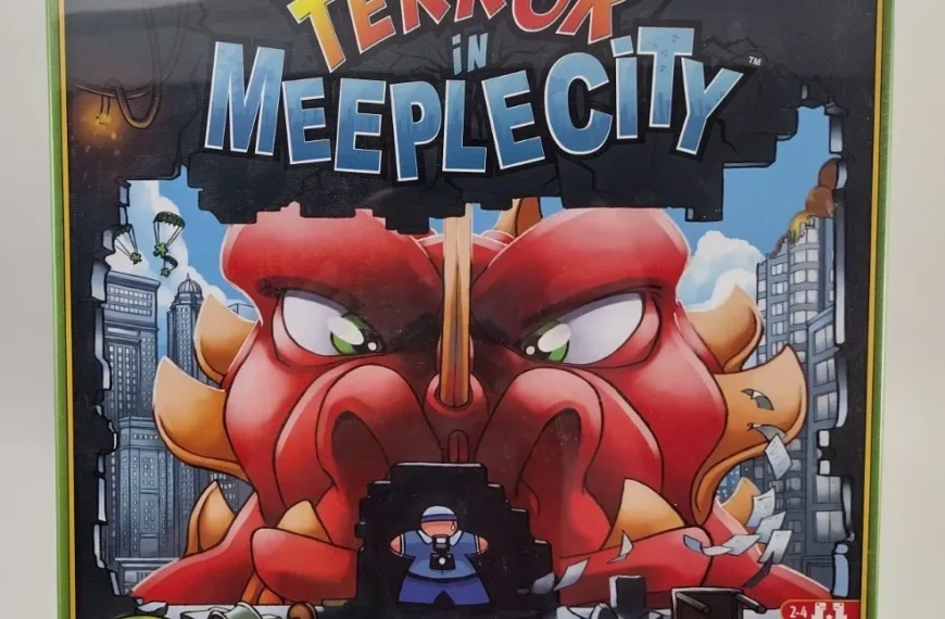 Board game box cover for "Terror in Meeple City" showing a stylized, angry red monster destroying a cityscape, with game details and logos around the edges.