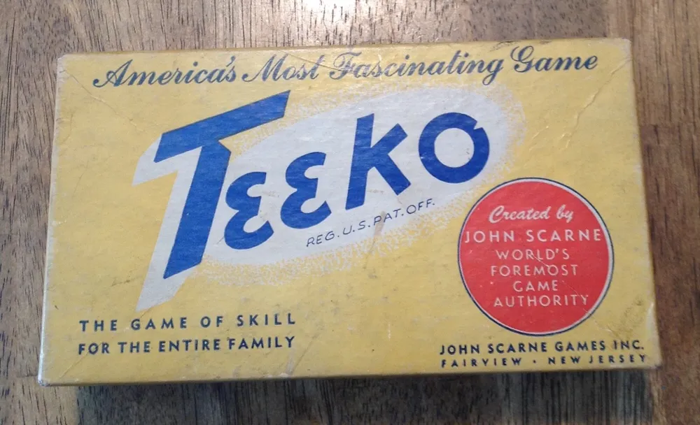 Vintage Teeko board game box with text "America's Most Fascinating Game" and "The Game of Skill for the Entire Family," highlighting creator John Scarne, labeled as the world's foremost game authority.
