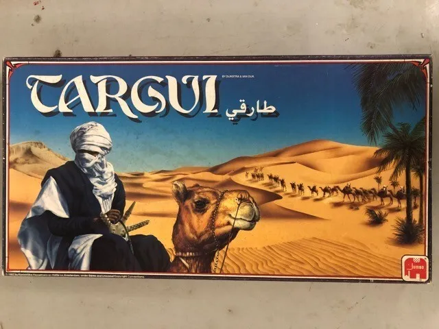 A board game box with the title "TARGUI" and Arabic script, featuring an illustration of a man in traditional attire riding a camel in a desert landscape with sand dunes and a caravan in the distance.