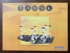 Box cover of the board game Tamsk, showing sand timer game pieces on hexagonal board tiles with the game's name in white letters at the top.