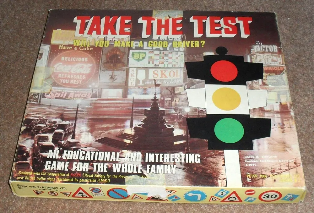 Board game "TAKE THE TEST" box depicting a collage of traffic-related images with a prominent traffic light and text proclaiming it an educational and interesting game for the whole family. Produced by Peter Pan Playthings Ltd. and made in England.