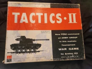 The image shows an old, worn board game box titled "TACTICS II" with a picture of a tank and text promoting the game as a realistic army group war game by Avalon Hill, suitable for adults and children 12 years and up. The Avalon Hill Company logo is visible at the bottom left.
