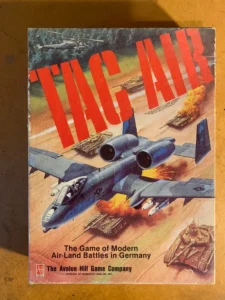 Alt text: An image of a vintage board game cover titled "Tac Air – The Game of Modern Air-Land Battles in Germany", published by The Avalon Hill Game Company. The artwork depicts a military jet in the foreground with tanks on the ground below engaging in combat.
