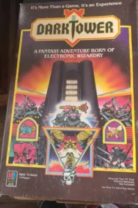 Box cover art for the electronic board game "Dark Tower" featuring a looming black tower against a red sky, surrounded by images of fantastical creatures and warriors. Text indicates it as a fantasy adventure game for ages 10 to adult, requiring two "D" size batteries.