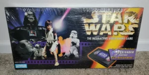 A "Star Wars: The Interactive Video Board Game" box featuring Darth Vader, Luke Skywalker, R2-D2, and a Stormtrooper, with a logo and tagline promoting never-before-seen Darth Vader footage, for ages 8 to adult by Parker Brothers, including an interactive VHS cassette.