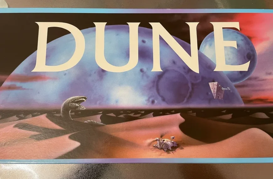 Promotional artwork for the movie Dune featuring large text "DUNE" over a desert landscape with a giant sandworm, a spaceship, and two figures in the foreground.
